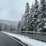 a road in the middle of a forest covered in snow