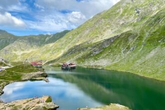 green mountains beside lake under blue sky during daytime