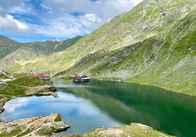 green mountains beside lake under blue sky during daytime